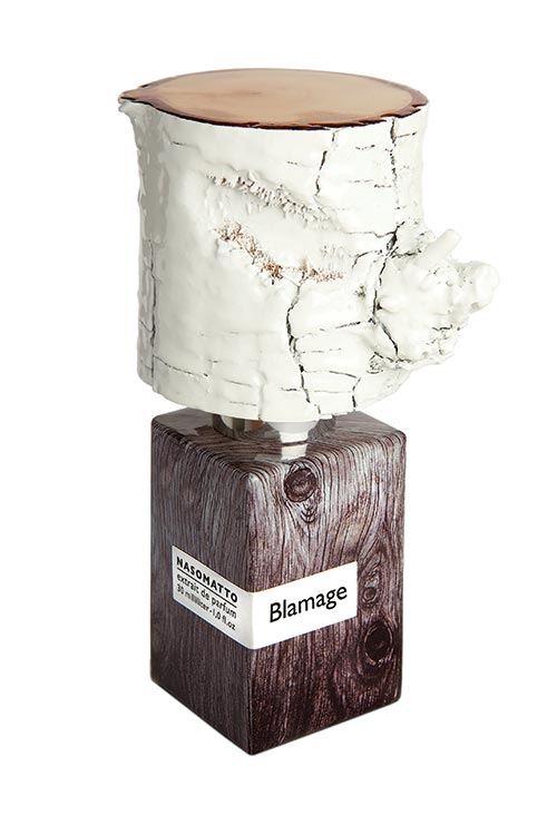 A bottle of Blamage by Nasomatto features a wooden texture and a white, textured cap that resembles a tree trunk.