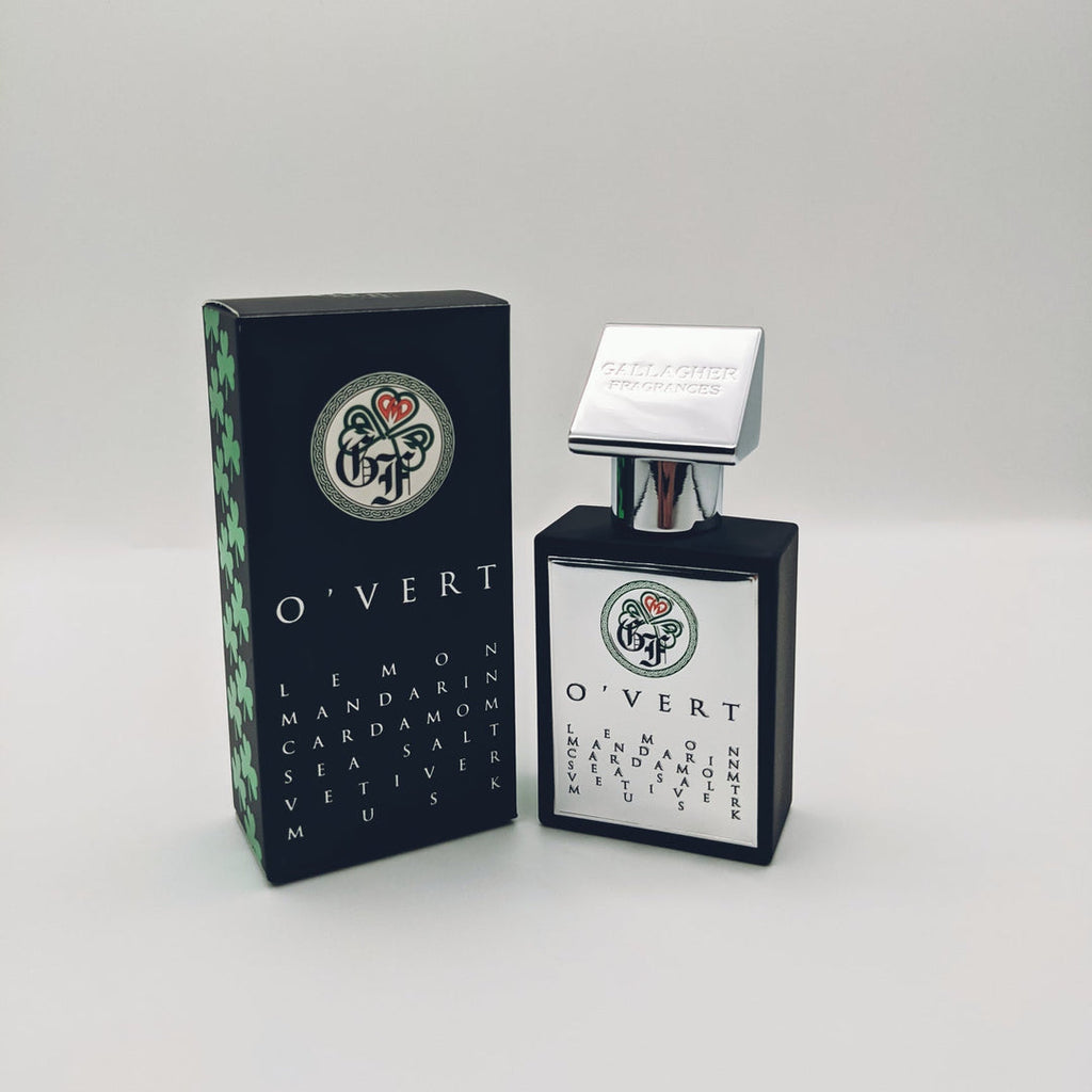A bottle of O'Vert fragrance by Gallagher Fragrances, featuring a white and black design, is displayed next to its matching black and green packaging. The fragrance notes include green mandarin, lemon, bergamot, sea salt, vetiver, and musk.