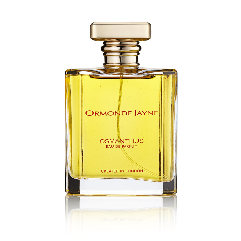 A square perfume bottle with a gold cap, labeled "Ormonde Jayne Osmanthus" and "Created in London," containing a yellow liquid that captures the essence of fruity floral white flowers.