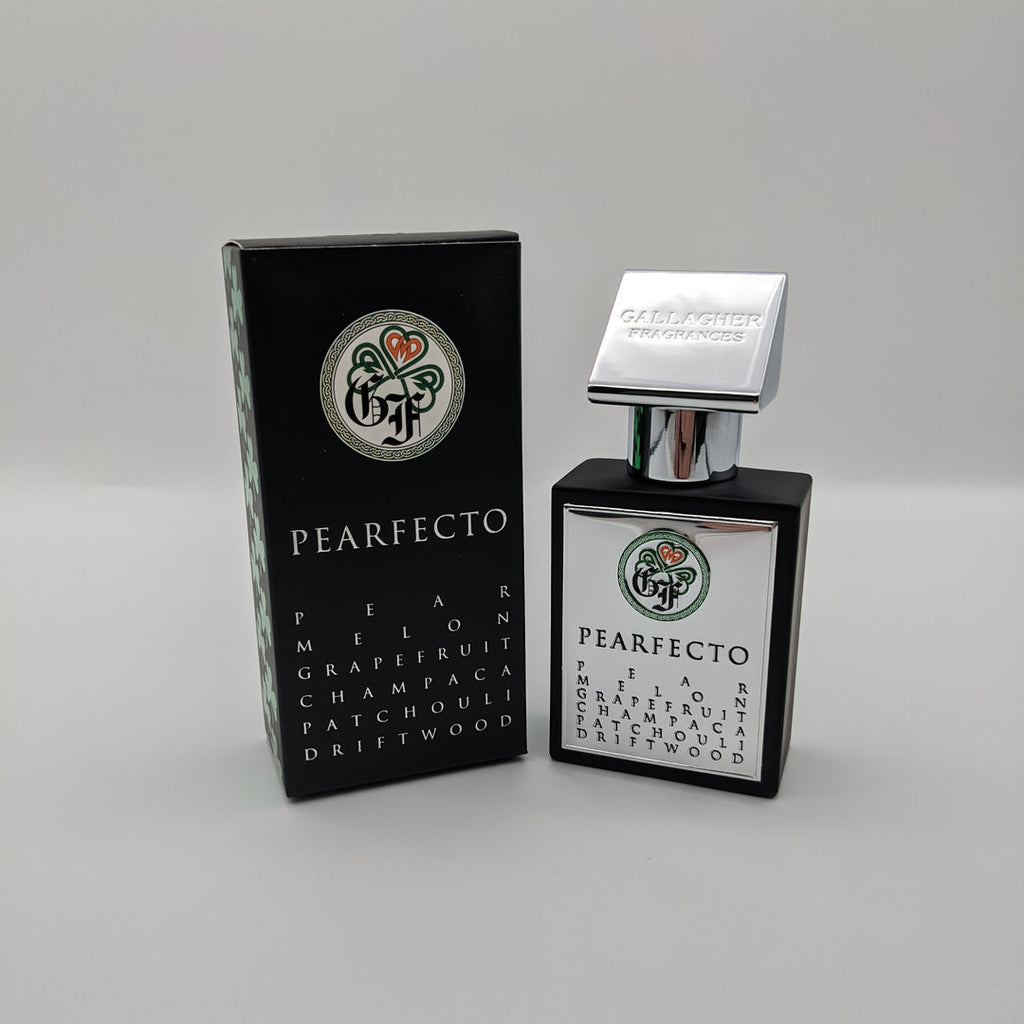 A black perfume bottle and matching packaging box, labeled "Pearfecto" by Gallagher Fragrances, offers an olfactory paradise with notes of pear, melon, grapefruit, and Red Champaca Absolute. The bottle features a silver cap and displays the brand logo on both the bottle and the box.