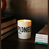 Lit white cylindrical candle with blue bands and PIONEER TASMANIA label