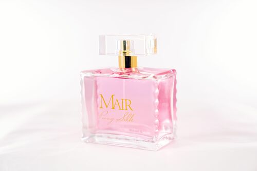 A glass perfume bottle filled with pink liquid, labeled "Peony Silk" by Mair. The bottle is rectangular with a clear, square cap and a golden neck. This elegant fragrance release features delicate florals and warm woods.