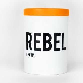 White candle jar with orange lid and black REBEL Bahia typography