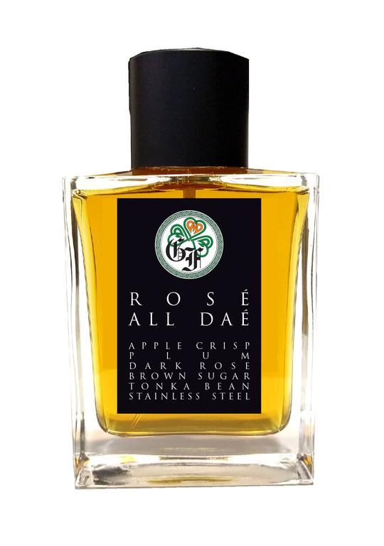 A perfume bottle labeled "Rosé all Daé" by Gallagher Fragrances with notes of apple crisp, rum, dark rosé, brown sugar, tonka bean, and stainless steel. This exquisite eau de parfum features a hint of Turkish rose absolute. The rectangular bottle boasts a sleek black cap for an elegant finish.