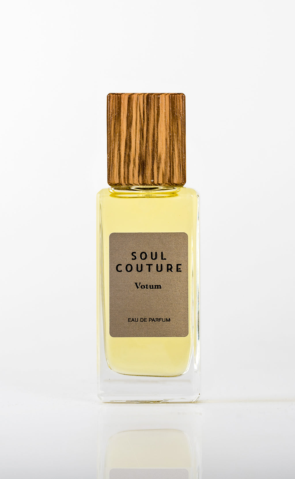 A glass bottle of Soul Couture's Votum, Eau De Parfum featuring a wooden cap and infused with the rich aroma of black tea.