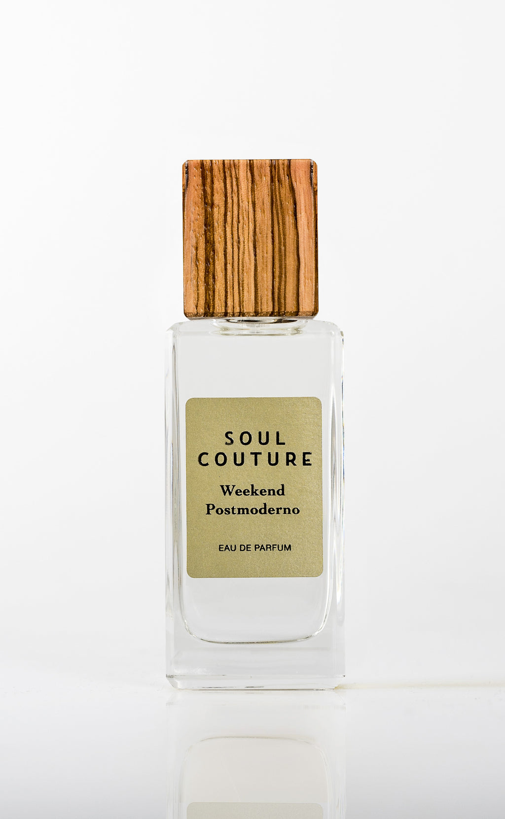 Clear glass perfume bottle labeled "Soul Couture Weekend Postmoderno" with a wooden cap, featuring subtle notes of cardamom.