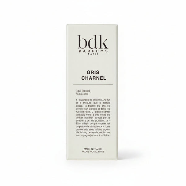 A white packaging box with the brand name "BDK Parfums" and the fragrance name "Gris Charnel" printed on it, enhanced by descriptive text in French. It evokes serene strolls through Jardin des Plantes and hints of sandalwood from India.
