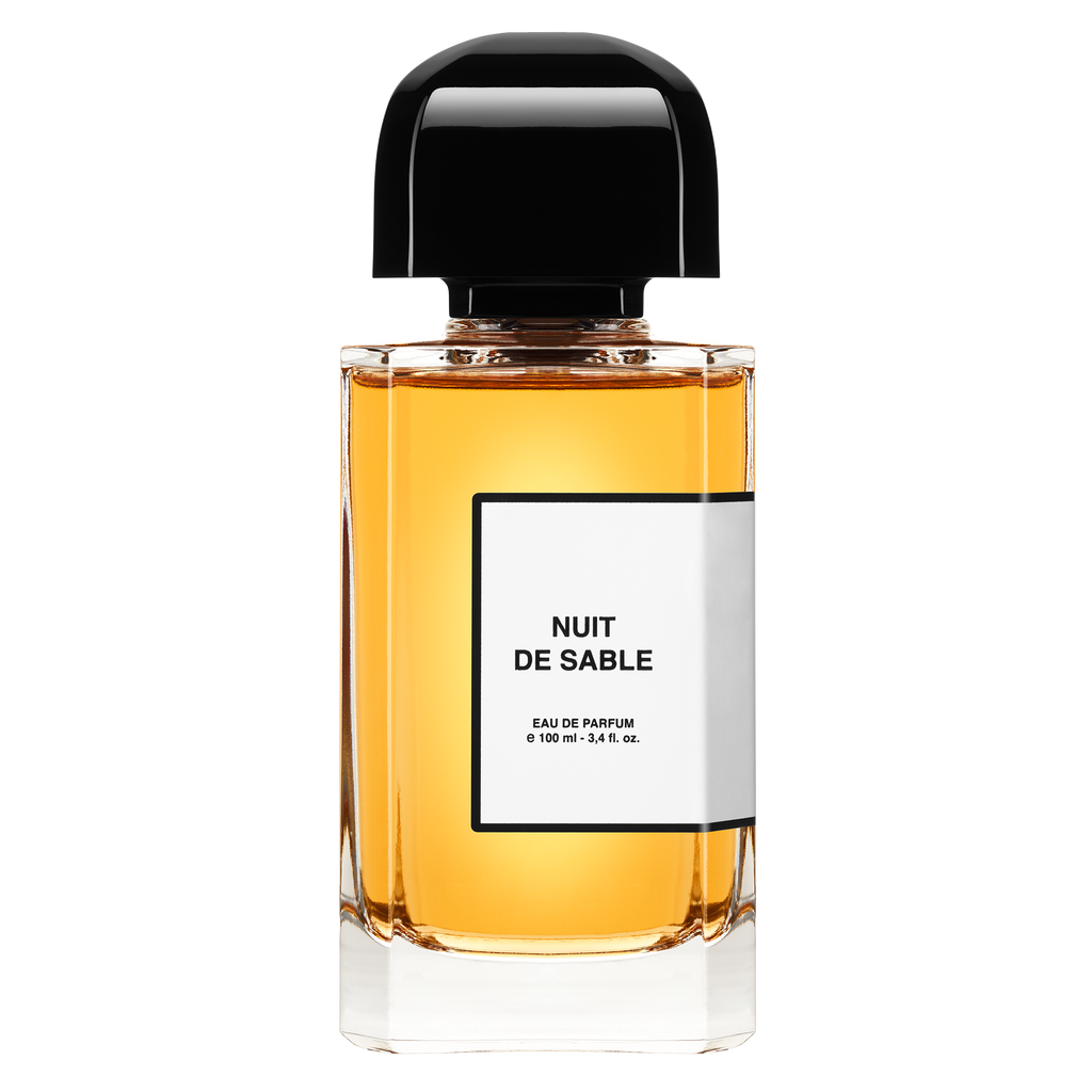 A 100 ml bottle of BDK Parfums' Nuit De Sable eau de parfum, showcasing an amber-colored liquid and a black cap, with notes of Turkish Rose.