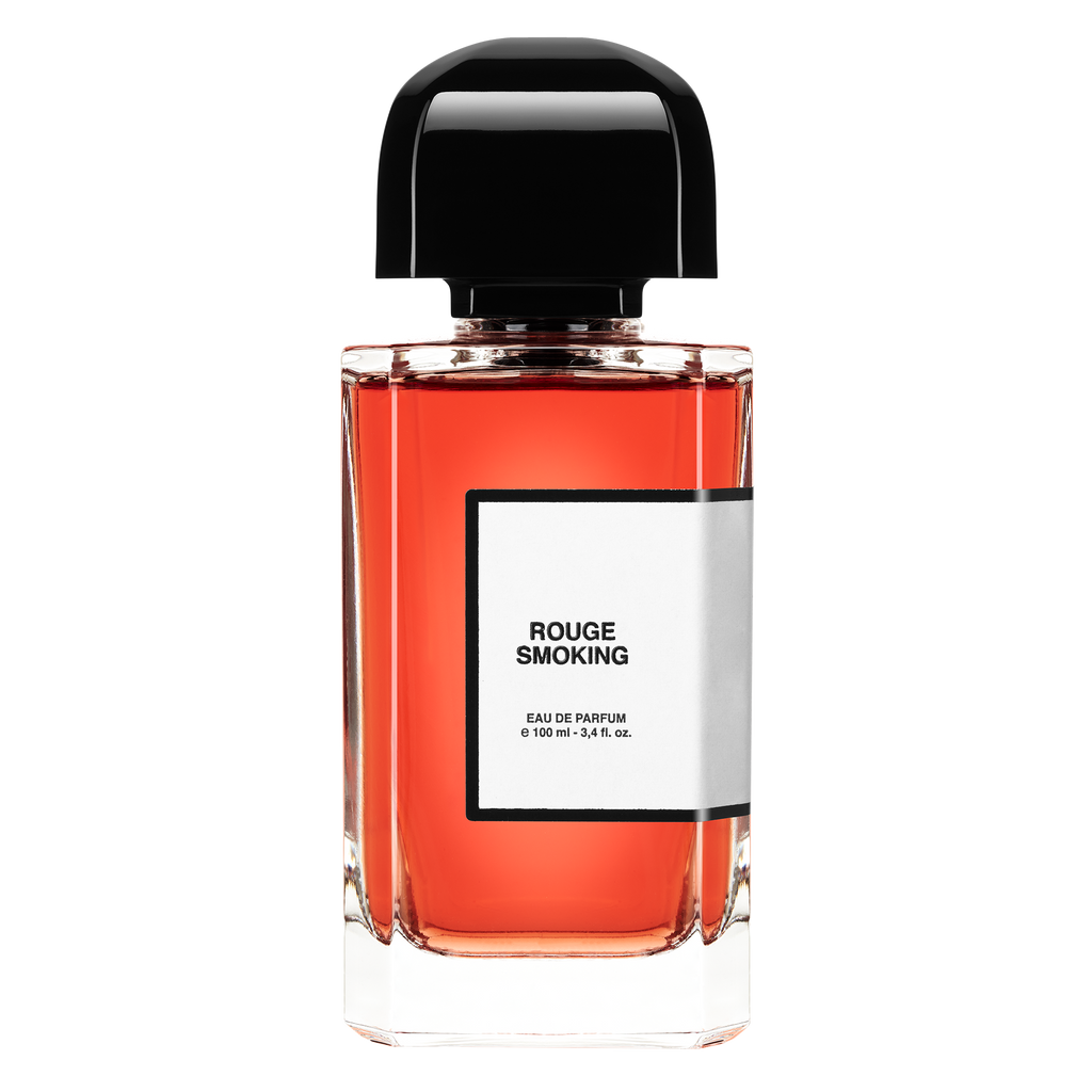 A clear glass bottle labeled "Rouge Smoking" by BDK Parfums containing a red liquid capped with a black lid, 100 ml, 3.4 fl. oz, evokes Parisian glam and sophistication.