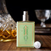 A bottle of Saint Julep by Imaginary Authors, featuring a decorative label and cap, sits on a wooden surface next to a cut glass decanter of bourbon with blurred glassware in the background.