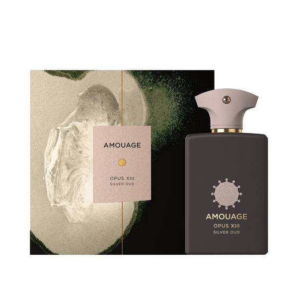 A bottle of Silver Oud fragrance by Amouage is displayed next to its packaging, featuring a minimalist design with green and beige abstract artwork and subtle hints of Patchouli.