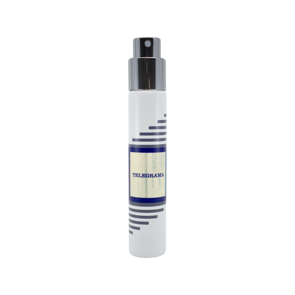 A white cylindrical spray bottle labeled "Telegrama" by Imaginary Authors, with a silver cap and horizontal gray and blue stripes on the label, exudes a plush scent reminiscent of a vintage first-class experience.