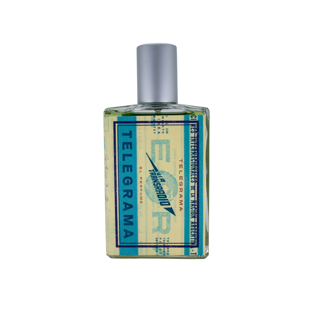A square glass bottle of perfume with a blue and yellow label that reads "Telegrama" and "Imaginary Authors," exudes a vintage first-class experience. The bottle, topped with a silver cap, contains a plush scent that leaves an impression as timeless as Lavender Absolute.