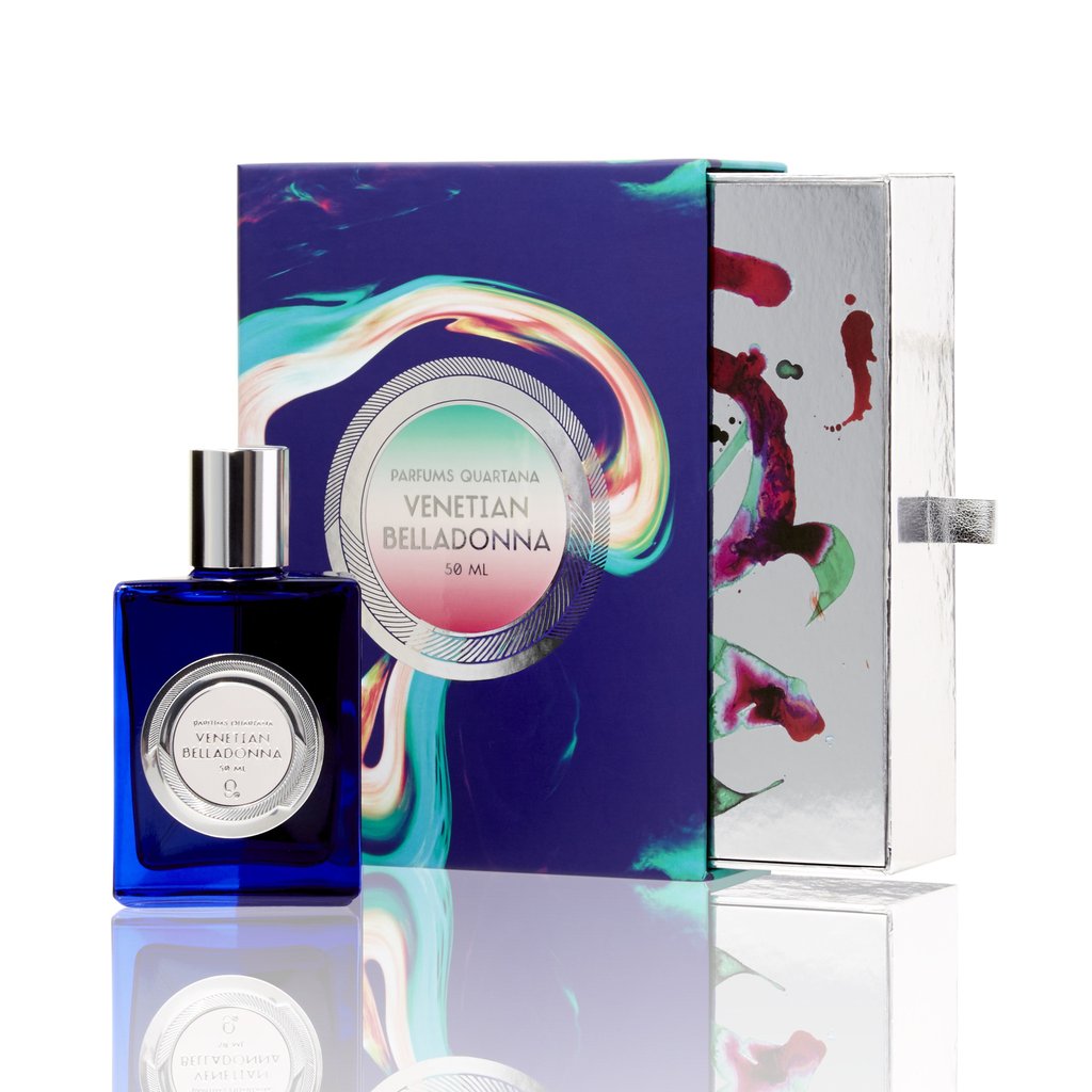 A blue glass bottle of Parfums Quartana's Venetian Belladonna rests beside its colorful, abstract-designed packaging. The bottle holds 50 ml of perfume and features a silver cap and label, reminiscent of elixirs once coveted by Italian witches.
