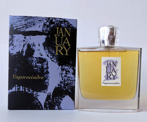 A bottle of "January Scent Project Vaporocindro" perfume sits next to its navy and black cardboard packaging. The bottle is rectangular with a clear stopper, emitting a subtle flower vapor scent. The packaging displays abstract, artistic designs.