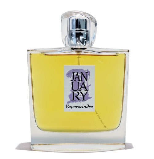 A clear glass perfume bottle filled with yellow liquid, adorned with a purple label that reads "Vaporocindro," exudes the essence of Flower Vapor Perfume from the January Scent Project.