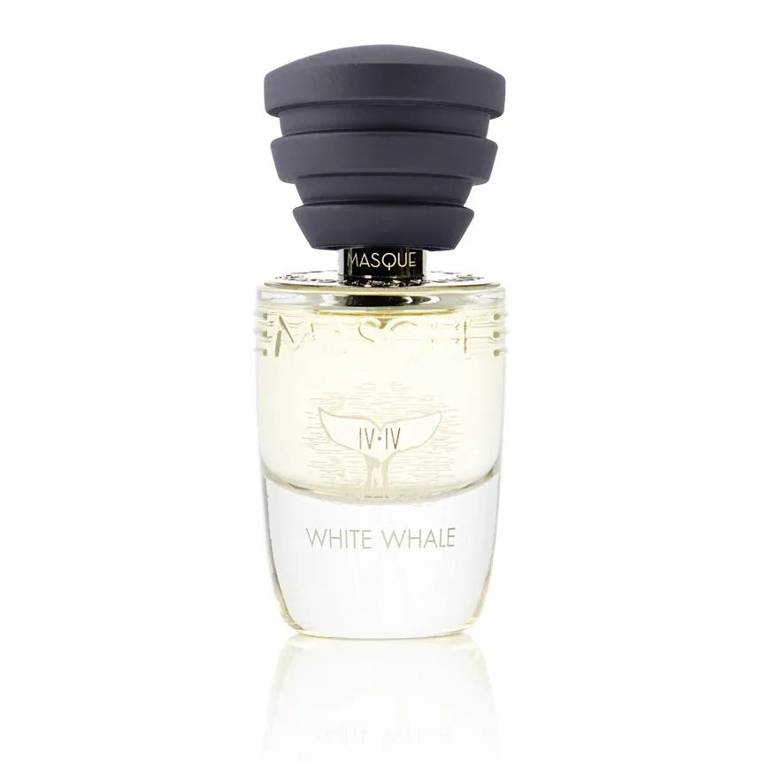 A bottle of Masque Milano's "White Whale" Eau de Parfum features a tiered black cap, a black "Masque" label near the top, clear glass showcasing light yellow liquid, and a whale tail logo with Roman numerals IV-IV. The fragrance hints at Osmanthus China LMR and Cedarwood Virginia.