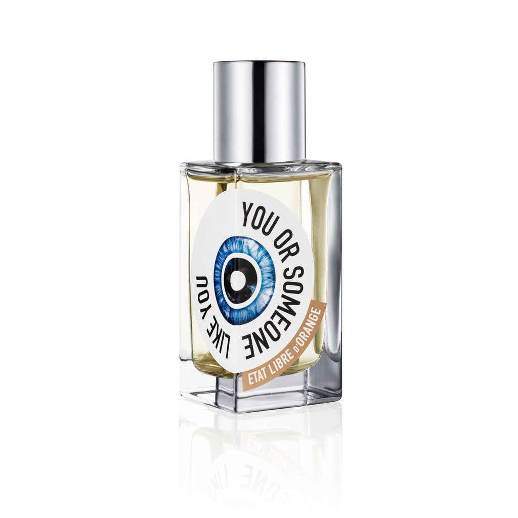 Bottle of "You or Someone Like You" perfume by État Libre d'Orange, with a blue eye graphic on the label and a silver cap. This fresh floral fragrance, curated by Chandler Burr, carries an air of sophistication and allure.