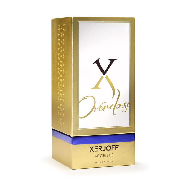 A gold and white rectangular box with "Xerjoff Accento Overdose" and "Xerjoff Accento Eau de Parfum" written on it features a blue band around its lower section, hinting at the captivating olfactory notes of the Accento Overdose perfume contained within.
