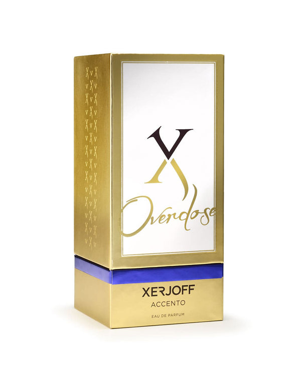 A gold and white rectangular box with "Xerjoff Accento Overdose" and "Xerjoff Accento Eau de Parfum" written on it features a blue band around its lower section, hinting at the captivating olfactory notes of the Accento Overdose perfume contained within.