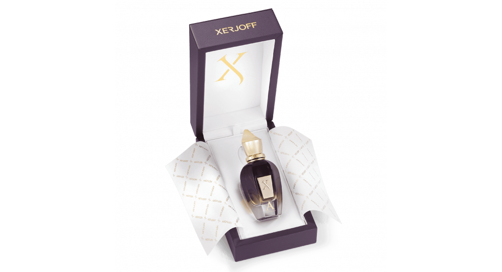 A luxurious perfume bottle encased in a purple and gold box, surrounded by patterned tissue paper. The bottle is labeled with the letter "X" and the box is branded with "Xerjoff." This exclusive oud perfume captures an oriental scent that transports you to Alexandria Orientale by Xerjoff.