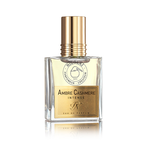 A clear glass bottle labeled "Ambre Cashmere Intense" with a gold cap and label, featuring the brand name "Nicolaï," captures the essence of an Oriental perfume with its contemporary fragrance that exudes fragrant amber.