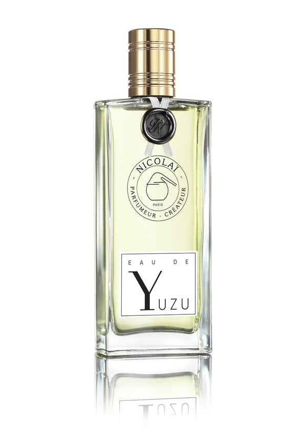 A clear rectangular perfume bottle with a gold cap labeled "Nicolaï: Eau De Yuzu," emanating the fresh, citrusy essence of yuzu.