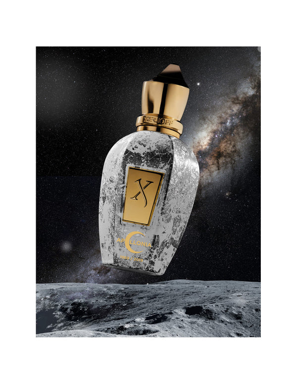A bottle of Apollonia by Xerjoff with a gold and marble design is positioned against a backdrop of deep space and the Milky Way galaxy, evoking the awe-inspiring moment of Apollo 11’s moon landing.