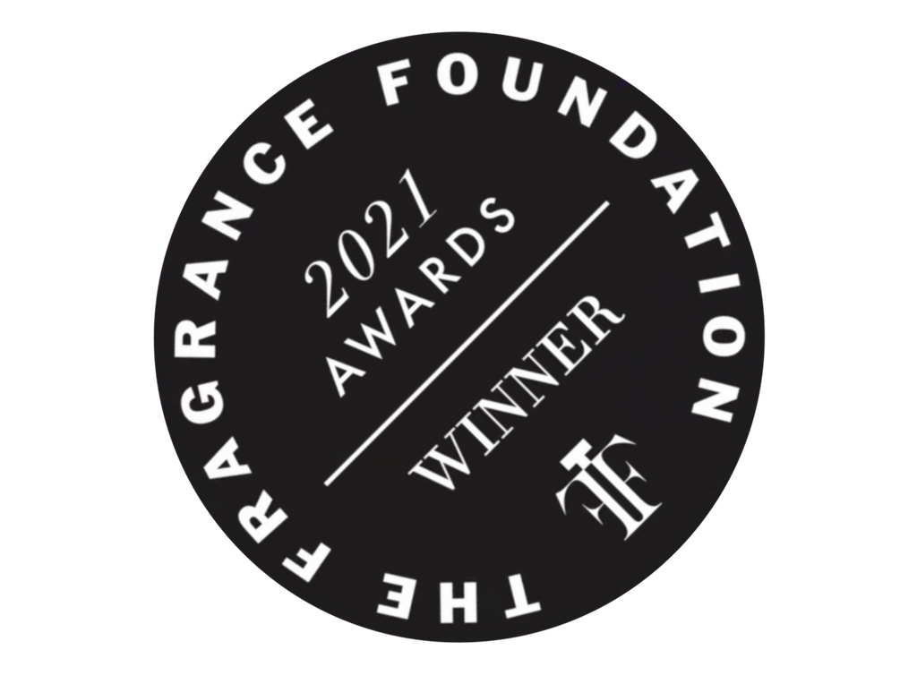 Black circular logo with "The Fragrance Foundation" around the edge, and "2021 Awards Winner" in the center, evoking notes of dark rum and plums from Scents of Wood's Plum In Cognac.