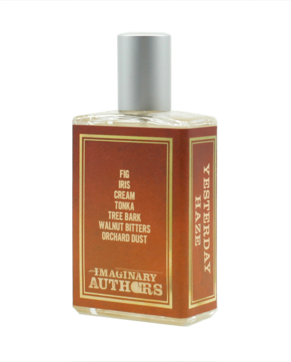 A bottle of Yesterday Haze perfume by Imaginary Authors. The label lists notes: fig, iris, cream, tonka, tree bark, walnut bitters, orchard dust. This seductive scent comes in a rectangular bottle with a metallic cap.