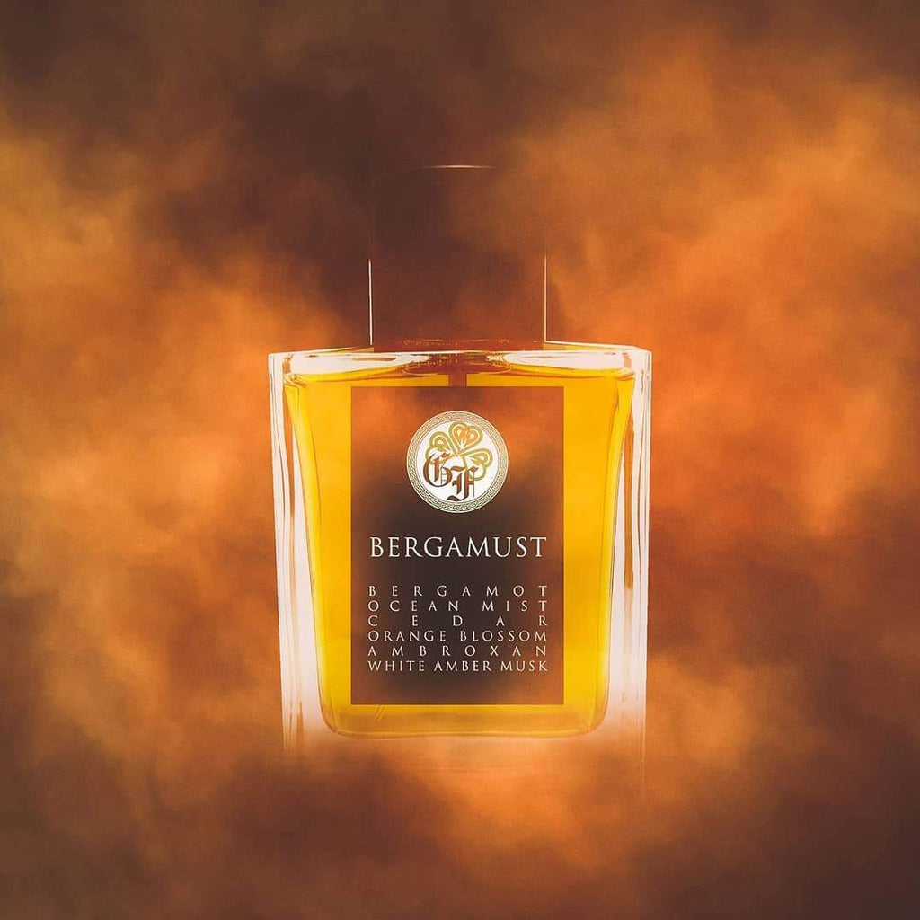 A square glass bottle with yellow liquid, labeled "Bergamust" by Gallagher Fragrances, offers an exquisite aquatic fragrance. It contains notes of bergamot, ocean mist, orange blossom, amber, oakmoss, and white amber musk, set against a smoky background.