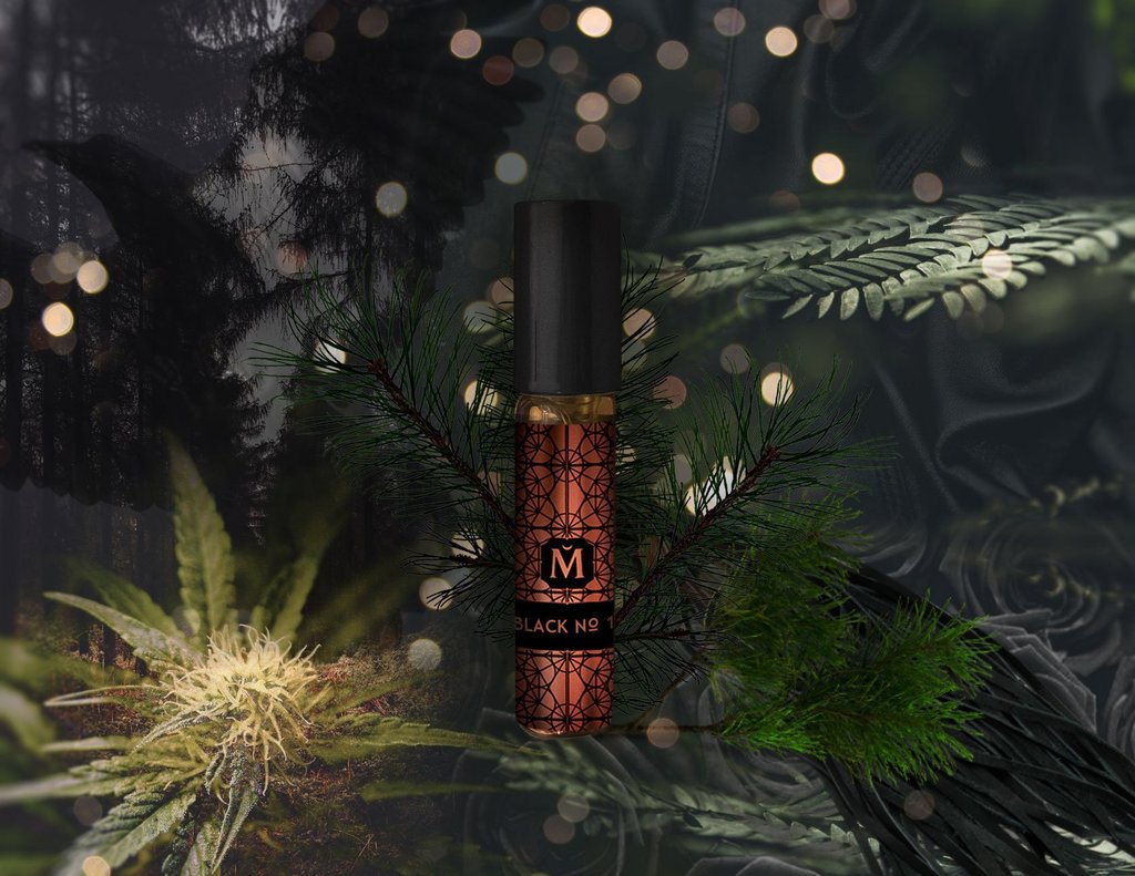 A perfume bottle labeled "Black No. 1 (Blackbird)" from House of Matriarch is surrounded by pine branches, against a background featuring blurred lights and dark foliage, hinting at the exotic natural essences within this men's fragrance.