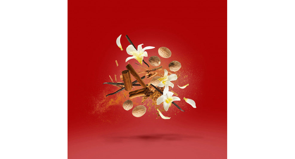 Floating ingredients on a red background, including vanilla flowers, cinnamon sticks, nutmeg, and a sprinkle of spice powder evoke the essence of Casamorati's Bouquet Ideale.