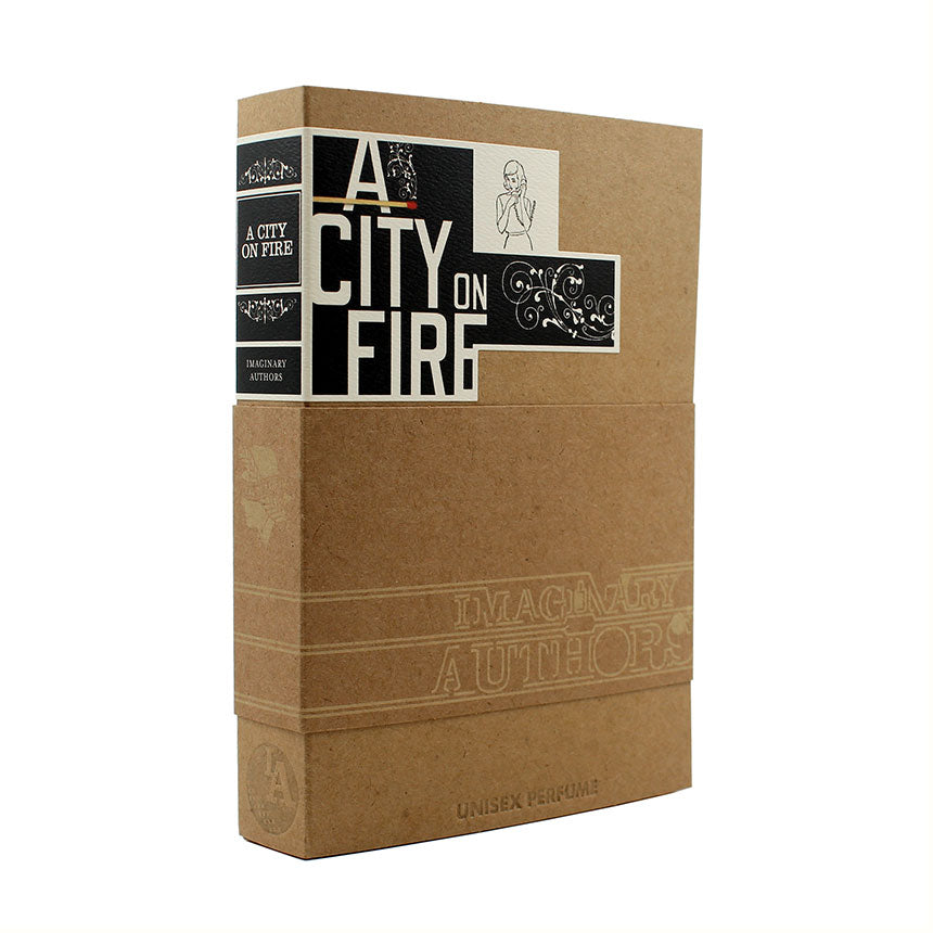 Image of a boxed perfume titled "A City On Fire" by Imaginary Authors. The brown box, enriched with black and white accents, features text and illustrated details, encapsulating the essence of refined smoke accord.