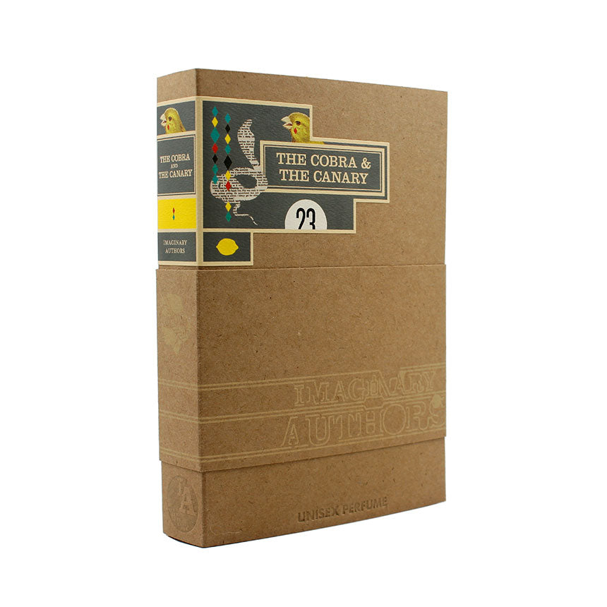 The Cobra & The Canary" by Imaginary Authors is presented in a beige box designed to resemble a book. Adorned with colorful graphics and text on the side, it captures the decadence and desolation of Palm Springs race tracks, paying homage to the 1964 Shelby Cobra Roadster.