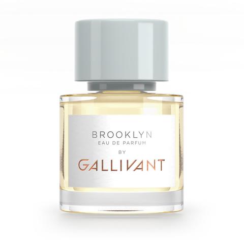 A bottle of Gallivant Perfumes Brooklyn by Gallivant with a light gray cap and a transparent glass body contains light yellow liquid. The label reads "Brooklyn by Gallivant by Gallivant Perfumes." This creative scent embodies the essence of a vibrant summer fragrance.