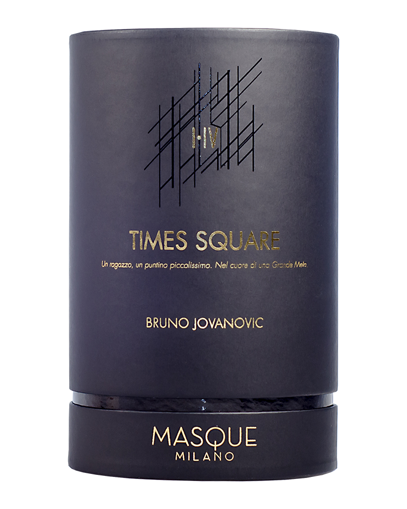A luxurious cylindrical container from Masque Milano, labeled "Times Square" and featuring the name Bruno Jovanovic in Italian text. The dark background is elegantly decorated with gold and white details, capturing the essence of New York’s city miasmas in a sophisticated perfume.