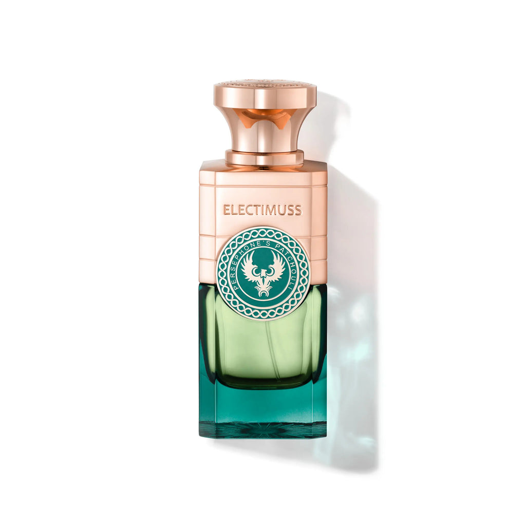 A bottle of Persephone's Patchouli by Electimuss, adorned with a copper-colored cap and a green and teal glass body featuring an ornate emblem on the front, exudes subtle hints of sandalwood in its perfumer's notes.