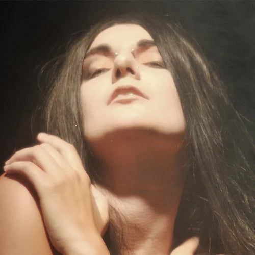 A person with long dark hair and pale skin poses with eyes closed, head tilted back, and arms crossed over their chest, evoking the allure of Ikiryo's "Je Te Veux.