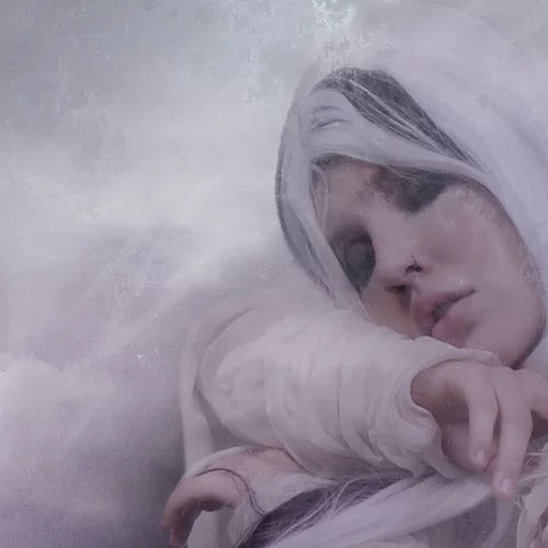 A person dressed in white with a serene expression is reclining against a soft, ethereal background, enveloped in the subtle scents of Drifting by Ikiryo, featuring notes of Lavender and Peru Balsam.