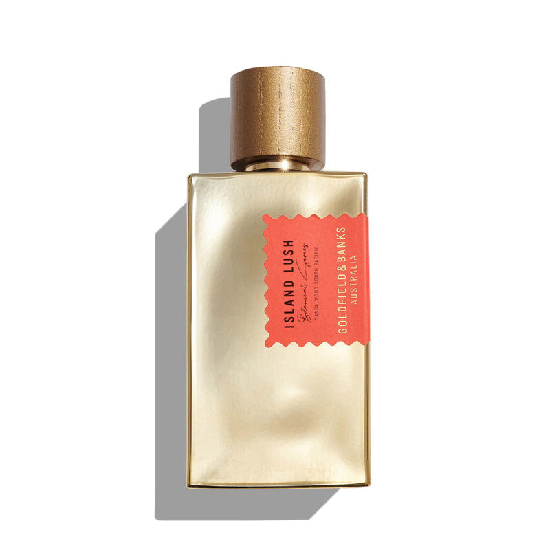 A gold rectangular perfume bottle with a gold cap and a red label that reads "Island Lush, Goldfield & Banks," captures the essence of an exotic fragrance enriched with South Pacific Sandalwood.
