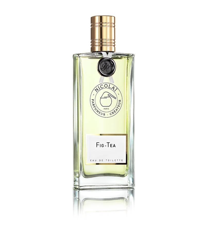 A glass bottle of Nicolaï Fig Tea Eau de Toilette featuring a gold cap, a label, and fragrant liquid inside. The label displays "Nicolaï Parfumeur-Créateur Paris" and "Fig Tea Eau de Toilette," capturing the essence of fig chord blended with notes of fruity tea.