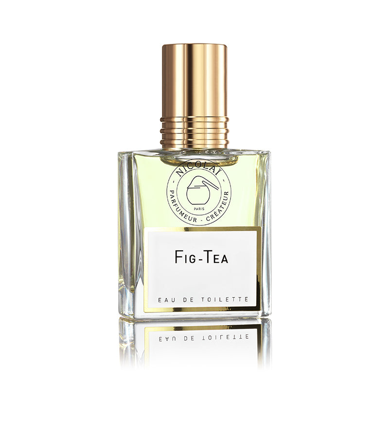 A bottle of Fig Tea Eau de Toilette by Nicolaï, featuring a transparent design with light yellow liquid inside and a gold cap. The fragrance beautifully blends jasmine and fig chord, adding depth to the fruity tea essence.