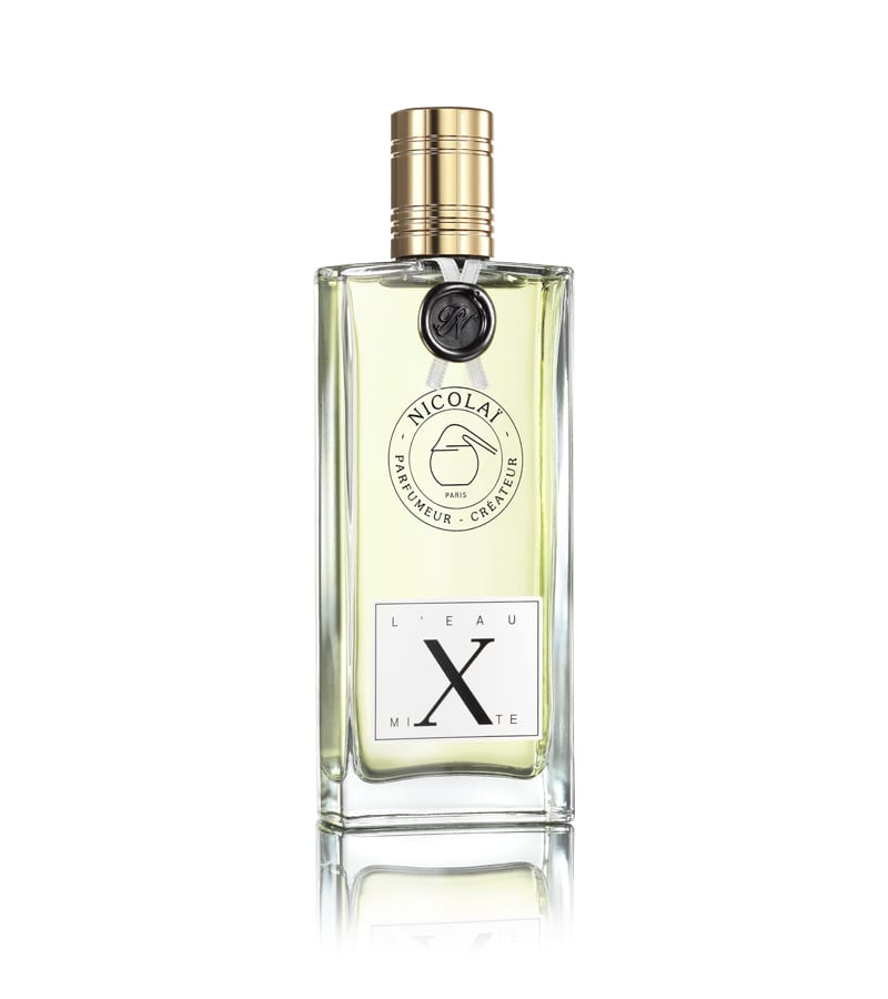 Clear glass bottle of Nicolaï L' Eau Mixte perfume with a gold cap, light yellow liquid inside, and labels at the front showing brand and perfume name. The fragrance boasts vibrant notes of Sicilian lemon and bergamot, evoking a fresh and invigorating scent experience.