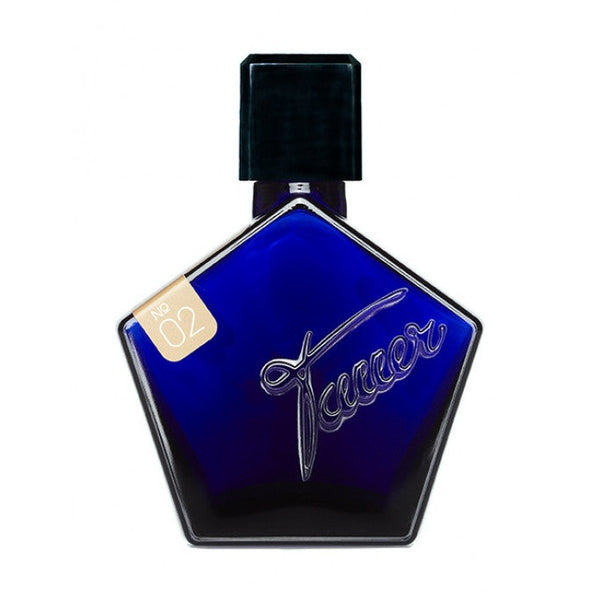 A cobalt blue, pentagon-shaped perfume bottle with a black cap and a label marked "No. 02 L'Air Du Desert Marocain" on the top left corner. The bottle, evoking a Moroccan night, has the word "Tauer Perfumes" engraved on the front.