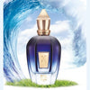 Image of a More Than Words perfume bottle by Xerjoff, housed in a blue design with a golden cap. It's set against an artistic backdrop of large waves and rests on a patch of green grass, evoking hints of oriental woods.
