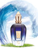 Image of a More Than Words perfume bottle by Xerjoff, housed in a blue design with a golden cap. It's set against an artistic backdrop of large waves and rests on a patch of green grass, evoking hints of oriental woods.