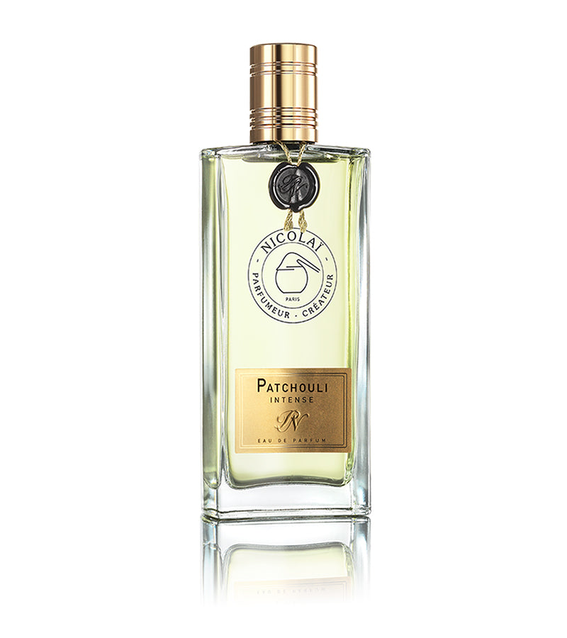 A bottle of Patchouli Intense perfume by Nicolaï, featuring a gold cap and label, infused with subtle hints of incense, designed by Nicolai Parfumeur Createur, displayed against a white background.