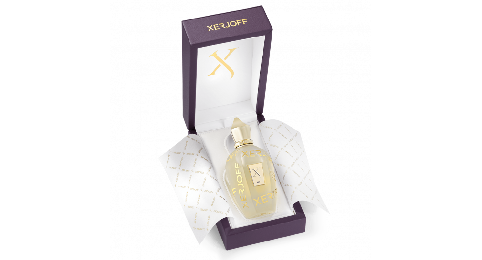 A bottle of Xerjoff's Sketchbook P. 33 perfume from the exclusive Sketchbook Collection in a partially opened purple box, with white and gold tissue paper. The bottle is clear with a gold cap and features a gold label on the front, exuding luxury with its floral and fruity notes.